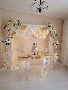 a wedding cake and flowers are on display in front of a backdrop with white lights