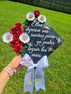 someone is holding up a graduation cap that has flowers on it and the words written in spanish