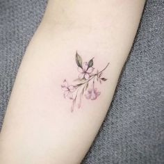 a small pink flower tattoo on the left arm