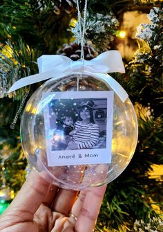 an ornament hanging from a christmas tree with a photo on it and a bow