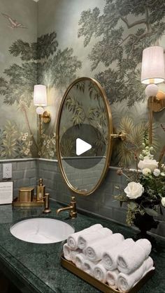 a bathroom with green marble counter tops and wallpapered walls, along with gold fixtures