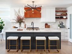 a kitchen island with stools in front of it and a chandelier hanging from the ceiling