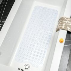 a white bath tub sitting on top of a tiled floor next to a towel and pillow