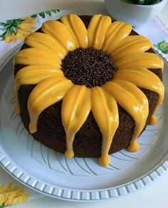 a cake with yellow icing on it sitting on a plate next to a potted plant