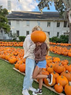 two people standing in front of a field of pumpkins with one person covering his face