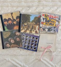 the beatles album covers are laid out on a white blanket and tied with a pink ribbon