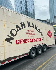 a large semi truck is parked on the side of the road in front of tall buildings