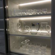 glassware is displayed on shelves in a display case