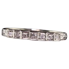 a white gold wedding band with five princess cut diamonds on the sides and four square shaped stones