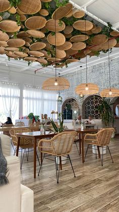 a room filled with lots of wicker furniture and plants hanging from the ceiling above