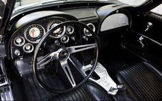 the interior of an old classic car with black leather and chrome trims, including steering wheel