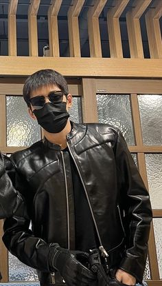 two young men wearing black leather jackets and masks, one with sunglasses on his face