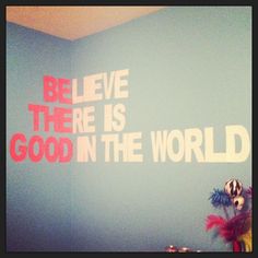 a blue wall with red and white lettering on it that says, believe there is good in the world