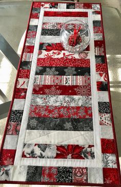 a table runner made with red and black quilted fabric, decorated with snowflakes