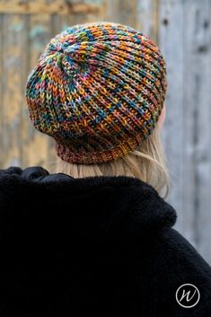 a woman wearing a multicolored knitted beanie hat with her back to the camera