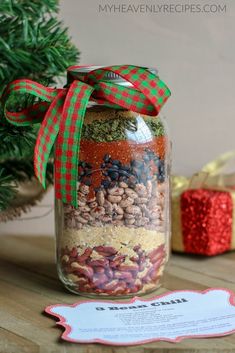 a jar filled with nuts and spices on top of a table next to a christmas tree