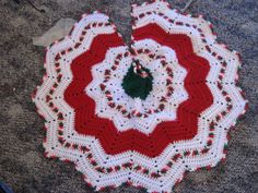 a red and white crocheted doily on the ground