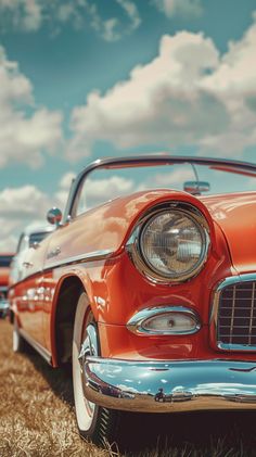 an old red car is parked in the grass