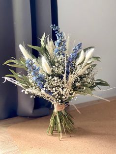 a bouquet of blue and white flowers sitting on the floor next to a window sill