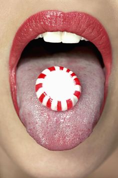 a woman's tongue with a candy cane sticking out of it