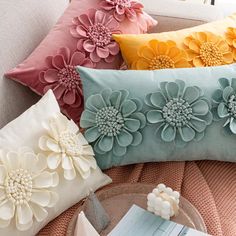 four pillows with flowers on them sitting on a couch