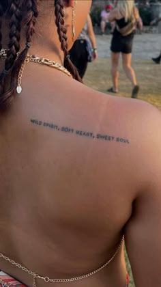 the back of a woman's shoulder with words written on it and people in the background