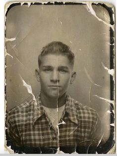 an old black and white photo of a young man wearing a plaid shirt with his tongue out