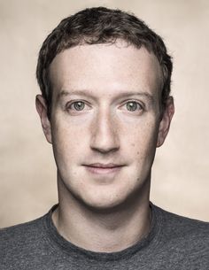 a close up of a person wearing a gray shirt and smiling at the camera with freckles on his face