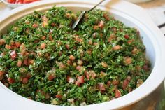 a white bowl filled with lots of food next to a plate full of tomatoes and broccoli