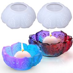 three colorful candles sitting next to each other on a white surface with one lit candle in the middle