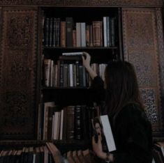 a woman standing in front of a book shelf filled with books