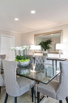 a dining room table with chairs around it and a vase filled with flowers on top