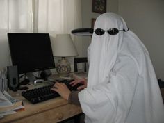 a person in a white robe is typing on a keyboard at a desk with a lamp