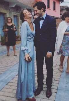 a man and woman standing next to each other on a sidewalk in front of buildings