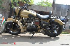 a tan and black motorcycle parked in front of a building