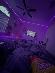 a bedroom with purple lights on the ceiling and a bed in front of a flat screen tv