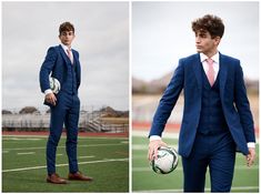 a man in a blue suit holding a soccer ball and wearing a pink tie, standing on a football field