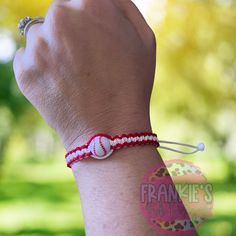 a person wearing a red and white bracelet with a baseball on it's wrist