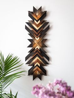 a wooden wall hanging with an arrow design on it and purple flowers in the background