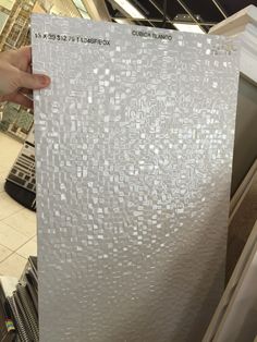 a person holding up a piece of paper with white squares on it in a store