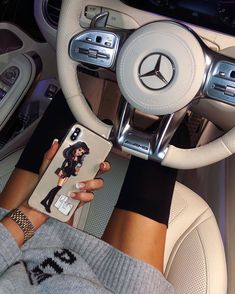 a woman is holding her phone while sitting in the driver's seat of a car