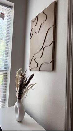 a vase with some flowers in it sitting on a white table next to a window