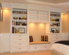 a bed room with a neatly made bed and white bookcases on the wall