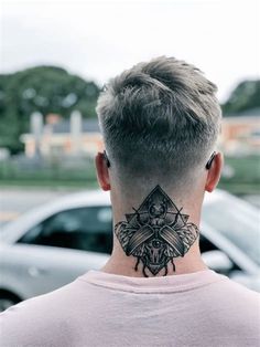 the back of a man's head with a tattoo on his neck in front of a parking lot