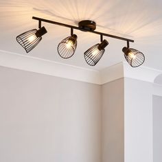 three light fixtures in a room with white walls and flooring, along with two windows