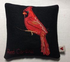 a black pillow with a red cardinal embroidered on it