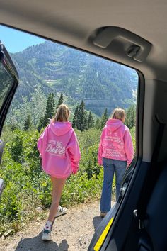 photo shows two teenage girls outside of a car in the mountains. the photo was taken from inside the car, but the backdoor is open so you can see the girls framed outside the car. they are walking away from the car. the girl in the back is wearing sneakers and an oversized hoodie that says "lets go on a drive" embroidered on the back in white. the girl in the front is wearing blue jeans and a pink hoodie that says "worldwide flower shop" embroidered on the back in white. there is a large mountai Dandy Worldwide, Spring Fits, Spring Vibes, Budget Wedding, Dandy, Let Go, Pink Flower, Flower Shop, Go On