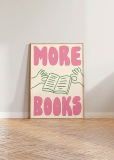 there is a sign that says more books in pink and green on the floor next to a white wall