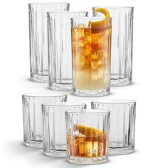 four glasses filled with different types of drinks and orange slices on the rims,