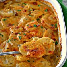 a casserole dish with potatoes and parmesan cheese in it on a green cloth